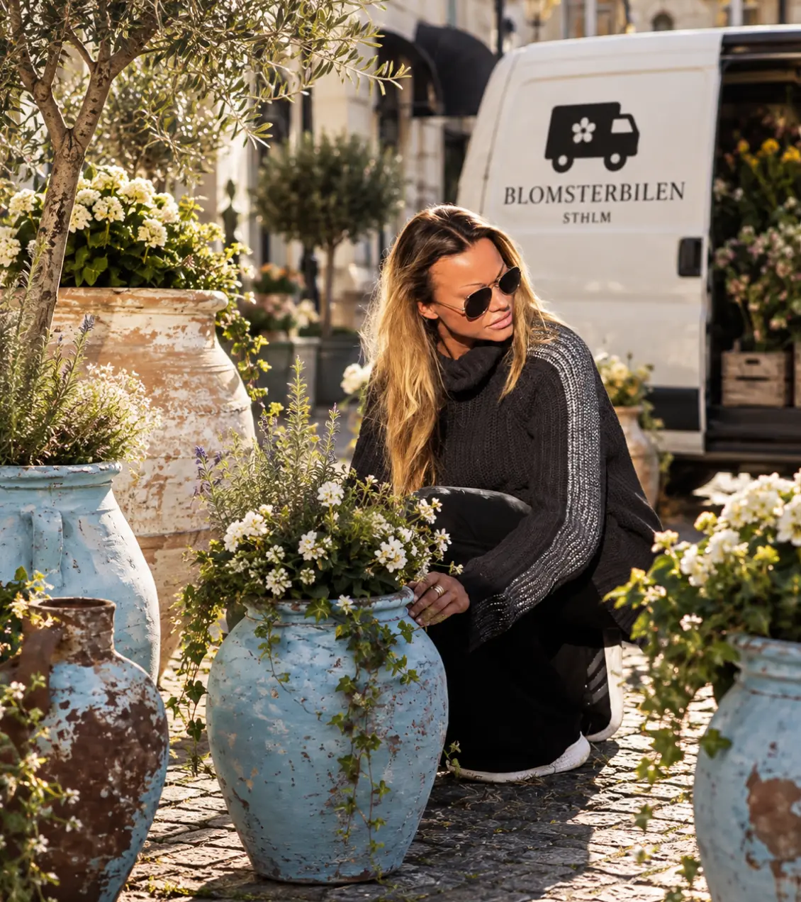 Linn planterar bland krukor utanför Blomsterbilens bil